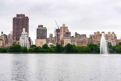 Buildings by river against sky in city