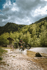 Man riding bicycle on mountain against sky