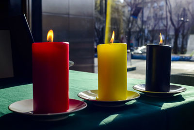 Lit candles symbolizing belgium flag on table at embassy building