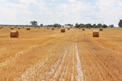 Hay bales on field against sky