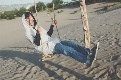 Woman sitting on swing at beach