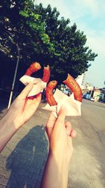 Low section of person holding shoe against trees