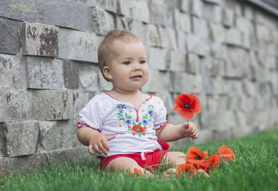 Portrait of cute baby boy sitting on stone wall