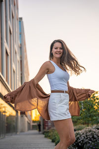 Portrait of young woman standing against trees