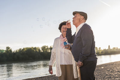 Senior man blowing soap bubbles on the beach at sunset