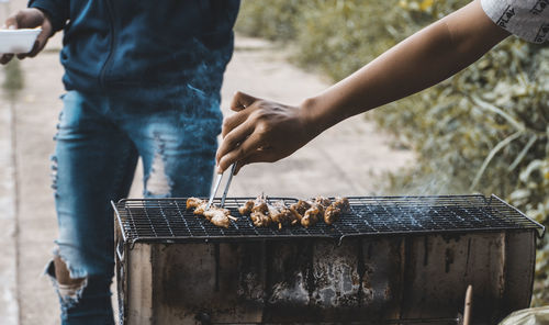 Cropped hand making food on barbecue grill