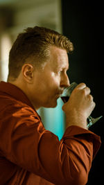 Side view of man drinking red wine at home