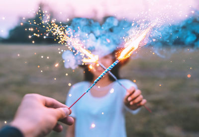 People holding illuminated fireworks on field