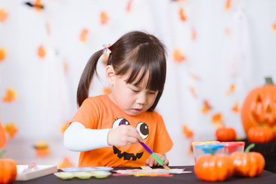 Young girl painting witch mask for halloween party at home