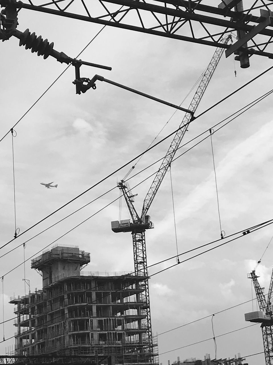 LOW ANGLE VIEW OF CRANES AND ELECTRICITY PYLON