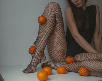 Sad woman in black lingerie ant fishnet tights with mandarins