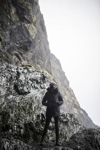Rear view of man standing on cliff against sky
