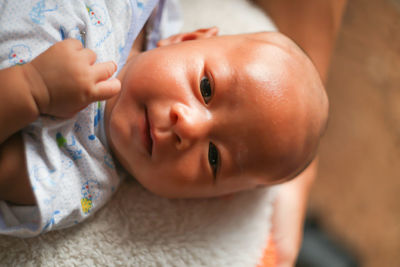 Close-up portrait of baby boy lying on bed