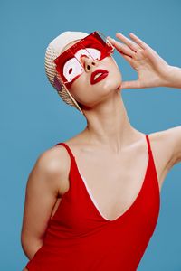 Portrait of young woman wearing hat against blue background