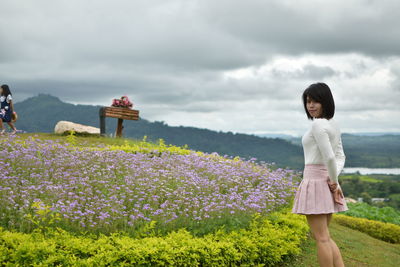 Portrait of woman standing by flowering plants in garden