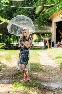 Rear view of woman with umbrella standing on field