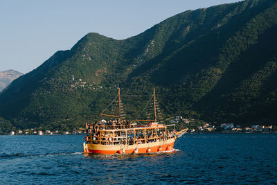 Sailboat sailing on sea against mountains