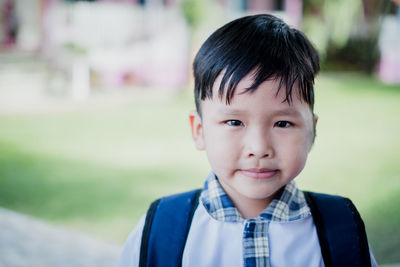 Portrait of cute schoolboy showing standing in park