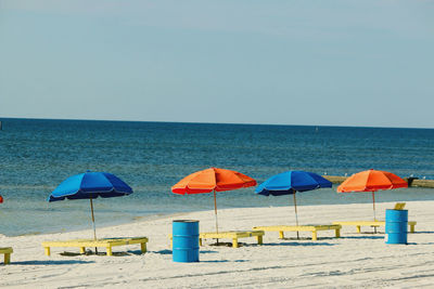 Deck chairs and parasols on beach against clear sky