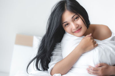 Portrait of a smiling young woman lying on bed