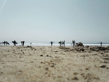 People walking on beach against clear sky