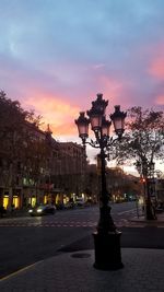 Illuminated street light in city against sky