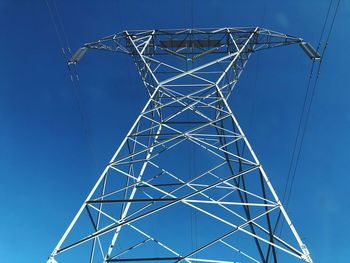 Low angle view of electricity pylon against blue sky