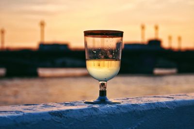 Close-up of beer glass on table against sky during sunset