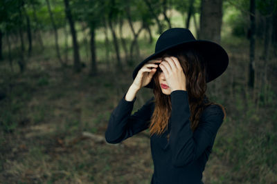 Young woman wearing hat standing in forest