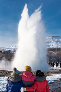 Rear view of people on mountain against sky