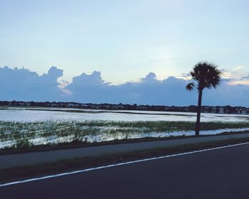 Scenic view of road by silhouette trees against sky