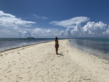 Rear view of woman on beach against sky