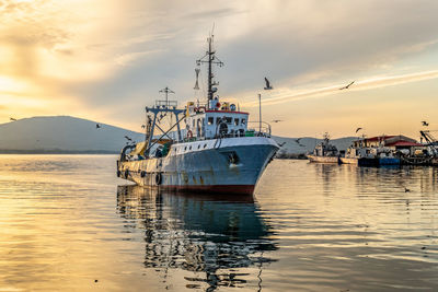 Fishing boat in sea against sky during sunset