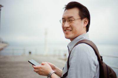 Portrait of smiling young man using mobile phone in city