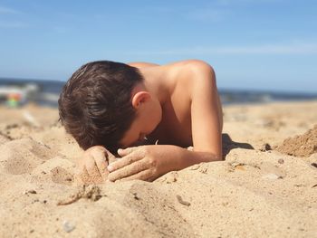 Boy on sand at beach against sky