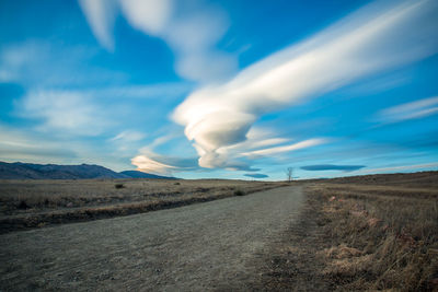 Road by landscape against blue sky