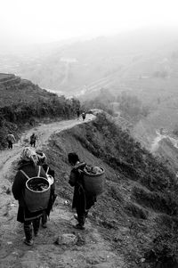 Rear view of people walking on mountain against sky