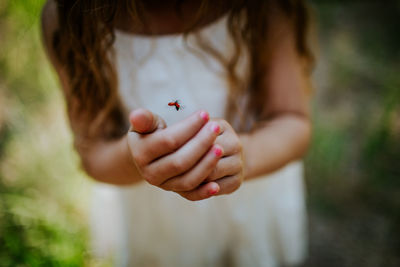 Close up of a ladybug flying out of young girl's hands