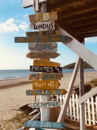 Information sign on beach against sky