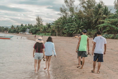 Rear view of people walking on beach