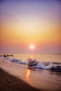 View of beach against sky during sunrise and fishermen coming back from the sea after fishing. 