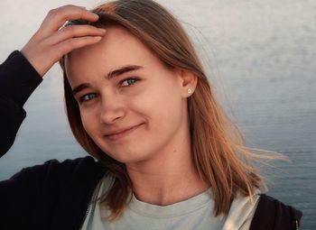 Close-up portrait of girl smiling while standing against sea