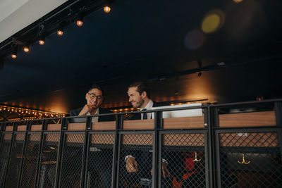 Smiling male professionals discussing while sitting in hotel lounge