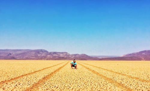 Rear view of woman standing on landscape against clear sky