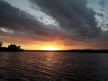 Scenic view of sea against dramatic sky during sunset