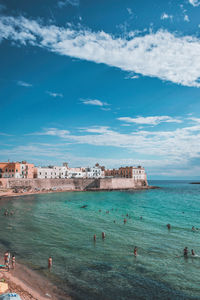 People on beach against blue sky