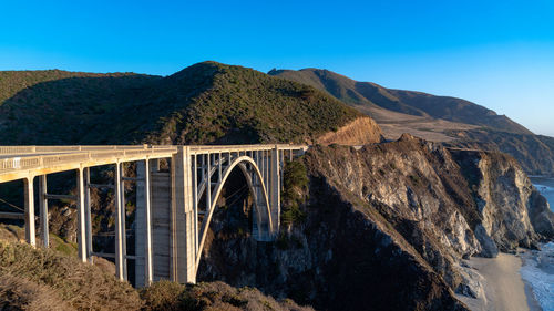 Arch bridge over mountains against clear sky