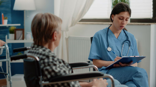 Side view of doctor using digital tablet while sitting in office