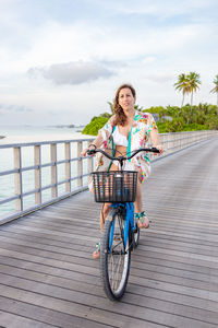 Portrait of young woman riding bicycle against sky