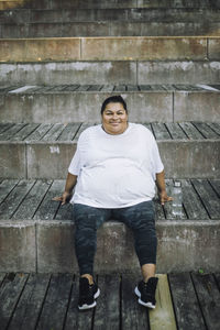 Portrait of smiling oversize woman relaxing on steps